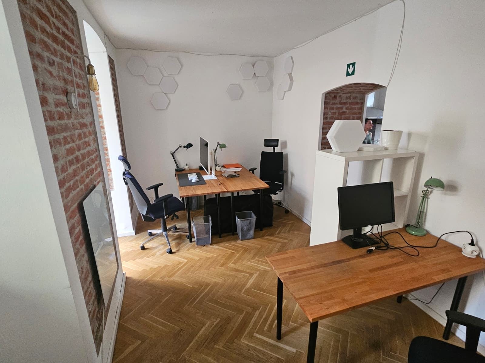 Heller Arbeitsraum mit Holztischen, Fischgrätparkett und Akustikpaneelen